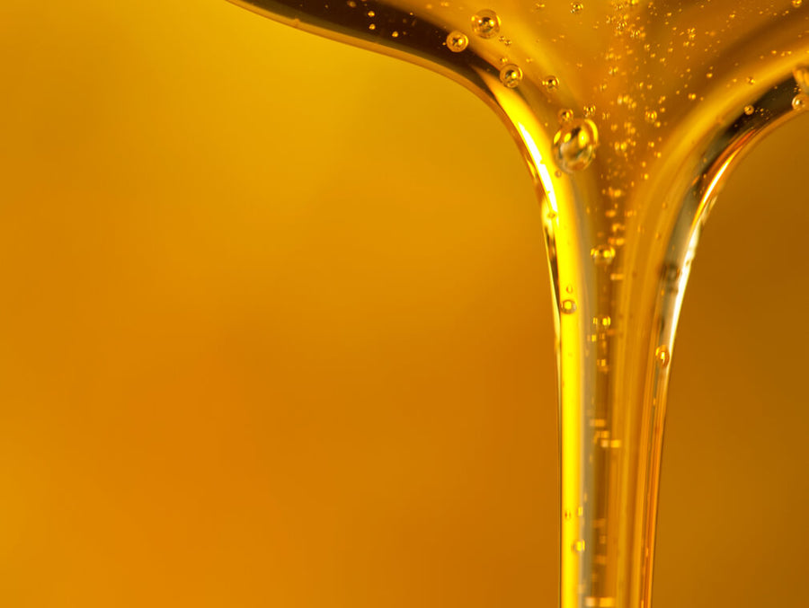 Pouring oil drop on golden background.