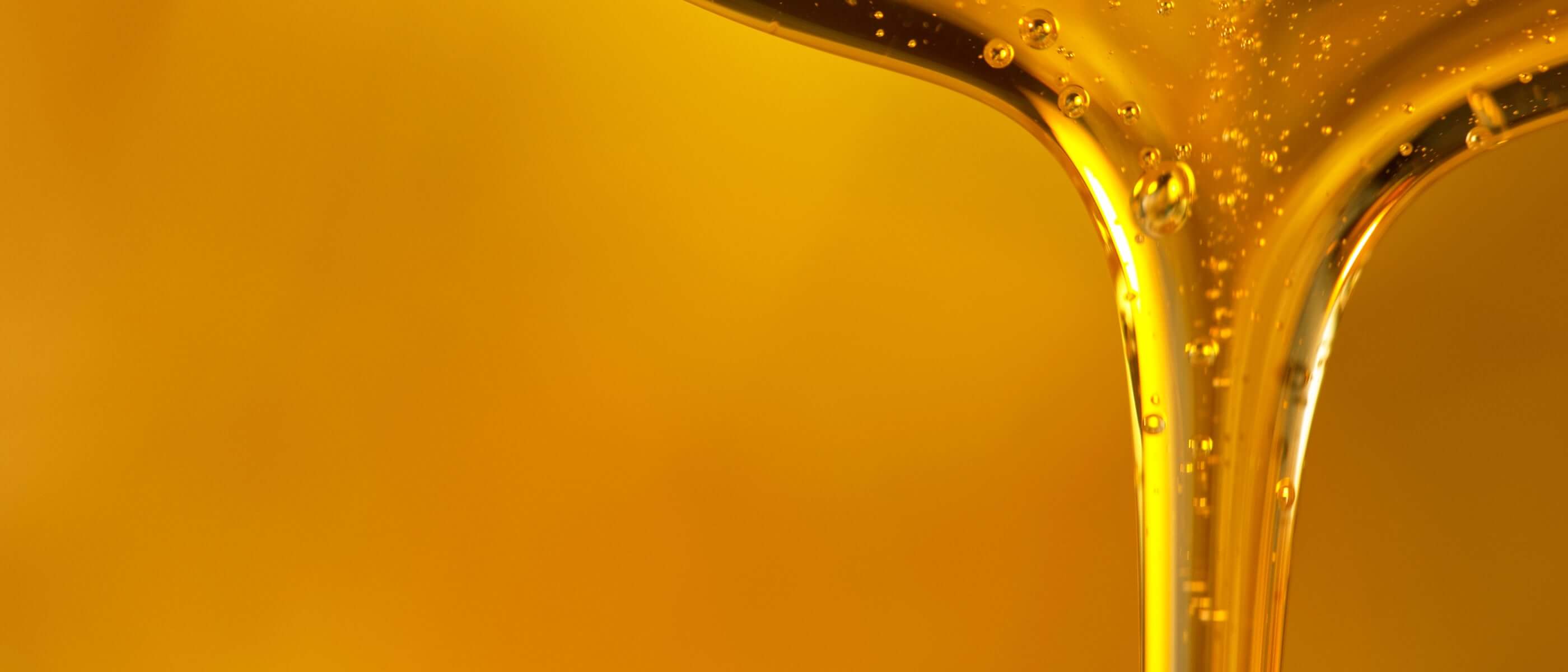 Pouring oil drop on golden background.
